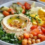 Creamy hummus on toast with avocado, eggs, and fresh veggies